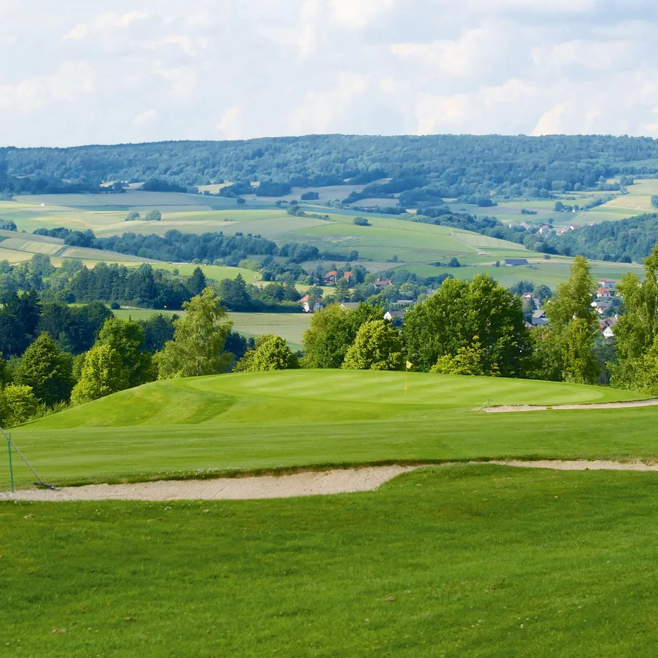 Grünes Golf-Putting-Green mit Sandbunker und weitem Blick über die hügelige Landschaft beim Parkhotel Zum Stern.