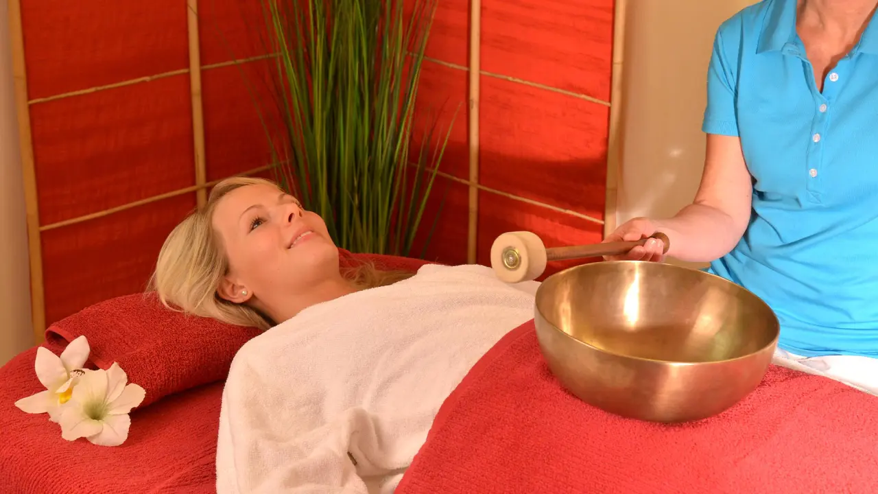 Entspannende Klangschalen-Therapie im Spa-Bereich des Parkhotel Zum Stern mit lächelnder Kundin.