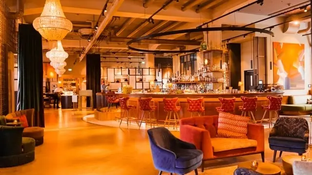 Stilvolle Hotelbar mit roten Samthockern und Kronleuchtern im Das James, einladend für entspannte Abende.