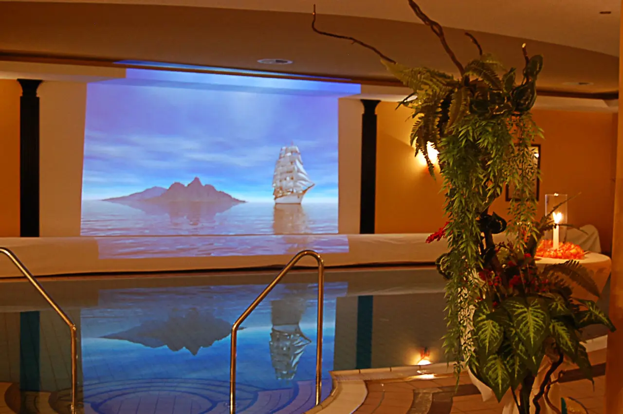Innenpool im Hotel Balneolum mit Wandprojektion von Segelschiff und Inseln. Entspannungsbereich.