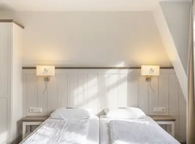 Helles Doppelzimmer mit Holzkopfteil und Nachttischen im Ringhotel Villa Margarete.