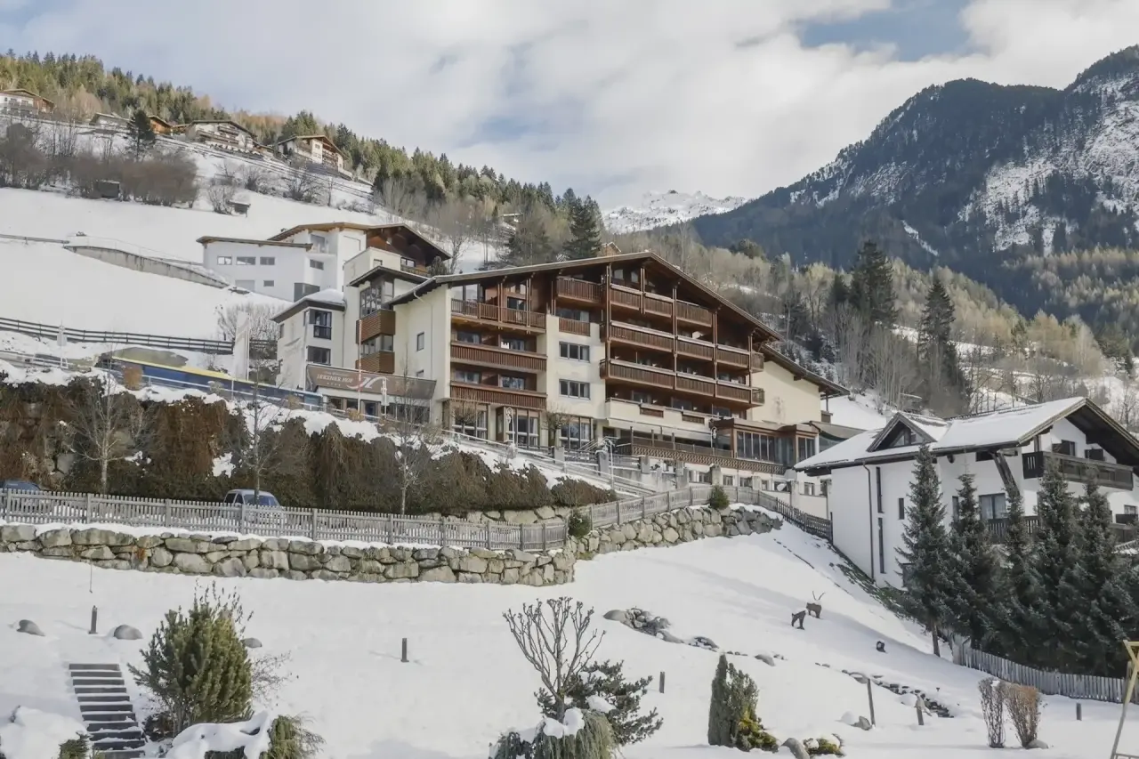 Aussenansicht des Hotels Jerzner Hof im Winter, umgeben von verschneiten Bergen und Tannen in Tirol.
