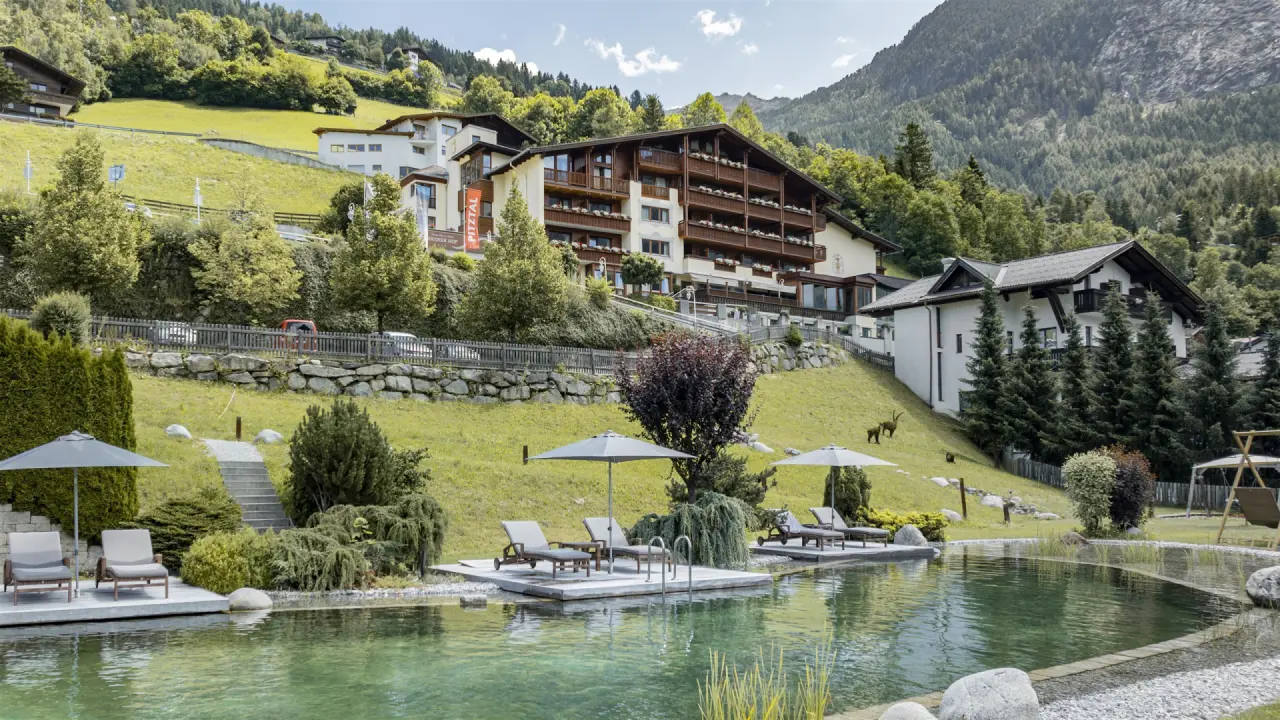 Panoramablick auf den Jerzner Hof mit Naturbadeteich, Liegebereichen und umliegender Berglandschaft im Pitztal.