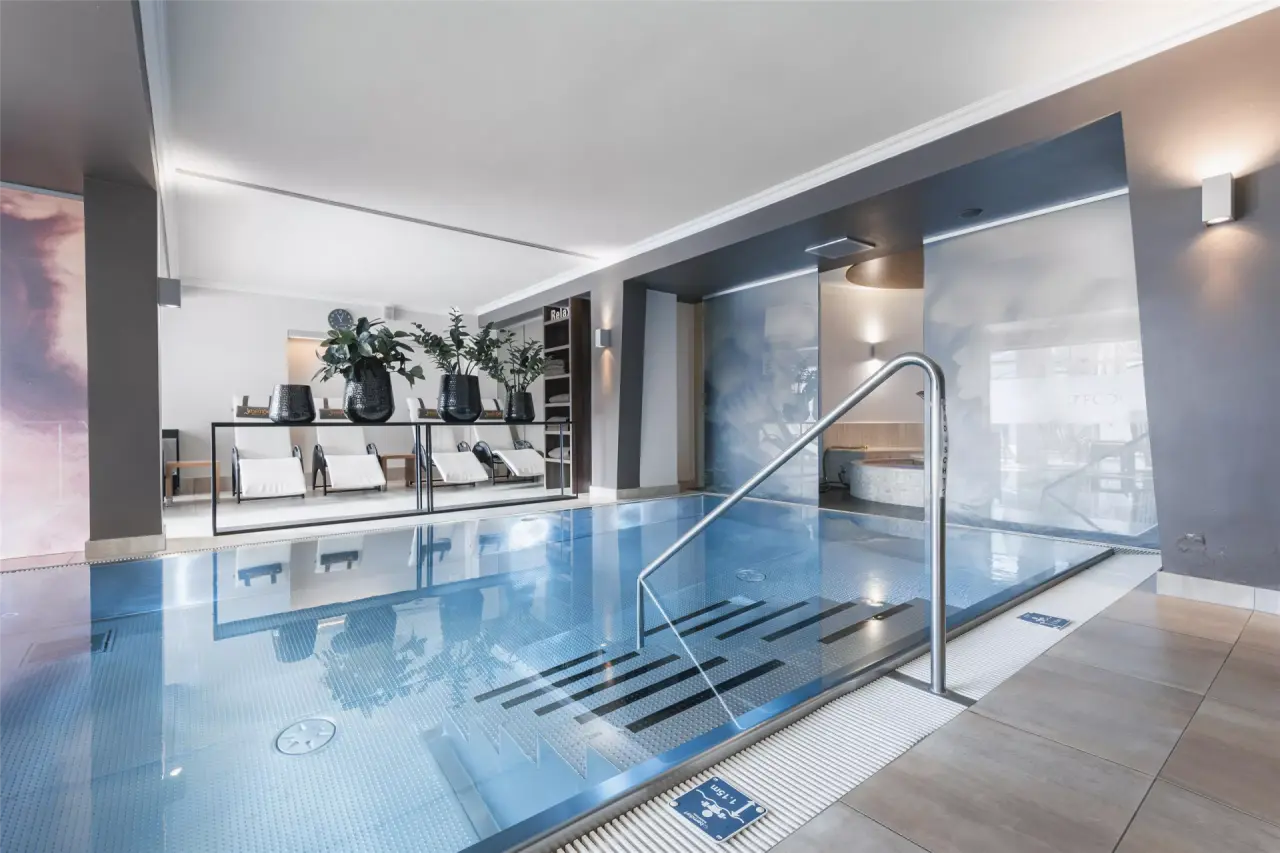 Modernes Hallenbad mit Entspannungsliegen im Wellnessbereich des Jerzner Hof Hotels.