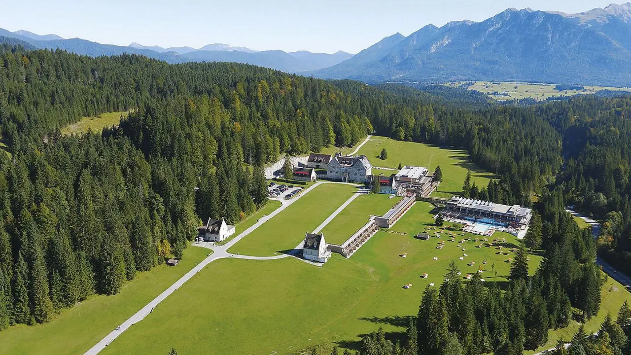 Luftaufnahme des Wellnesshotels Das Kranzbach in den bayerischen Alpen mit weitläufigen Grünflächen, Pool und Bergpanorama.