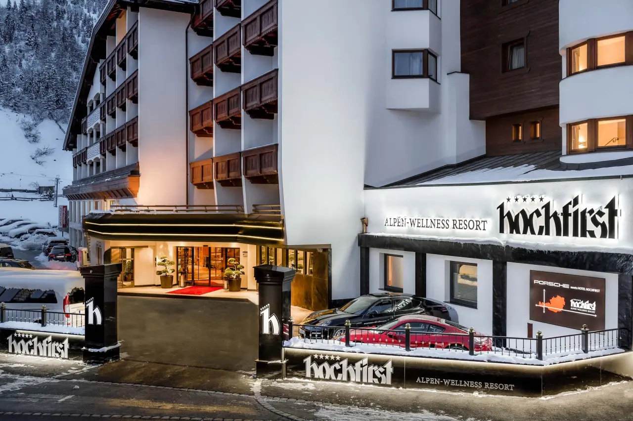 Beleuchtete Aussenansicht des Alpen-Wellness Resort Hochfirst im Winter mit verschneiter Umgebung und Eingangsbereich.
