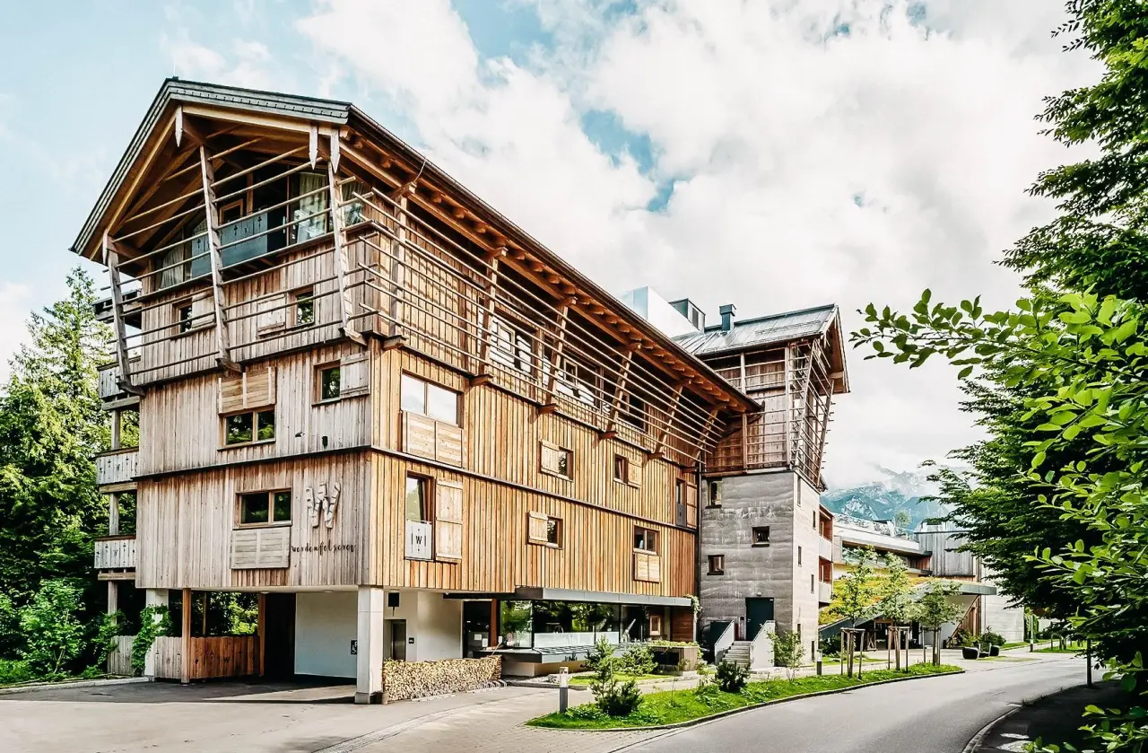 Moderne Holzarchitektur des WERDENFELSEREI Hotels in Garmisch-Partenkirchen mit Bergblick und grüner Umgebung.