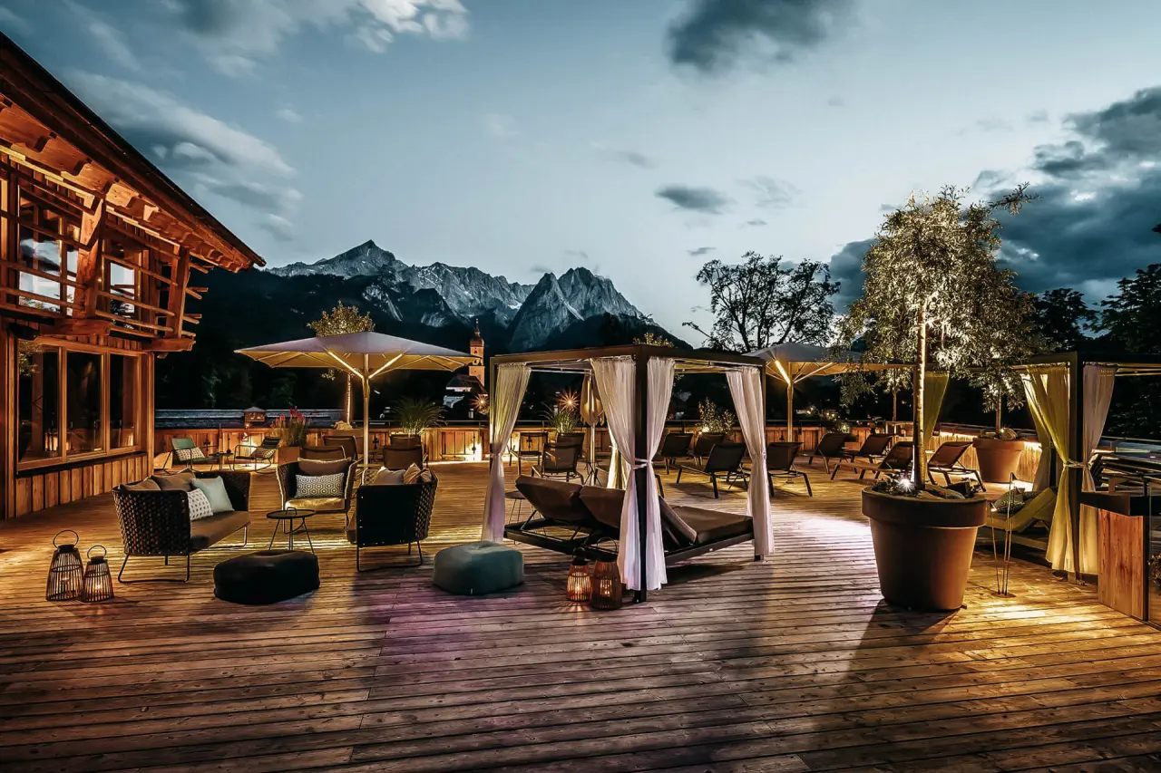 Luxuriöse Dachterrasse mit Lounge-Möbeln und Alpenpanorama im Hotel WERDENFELSEREI bei Sonnenuntergang.