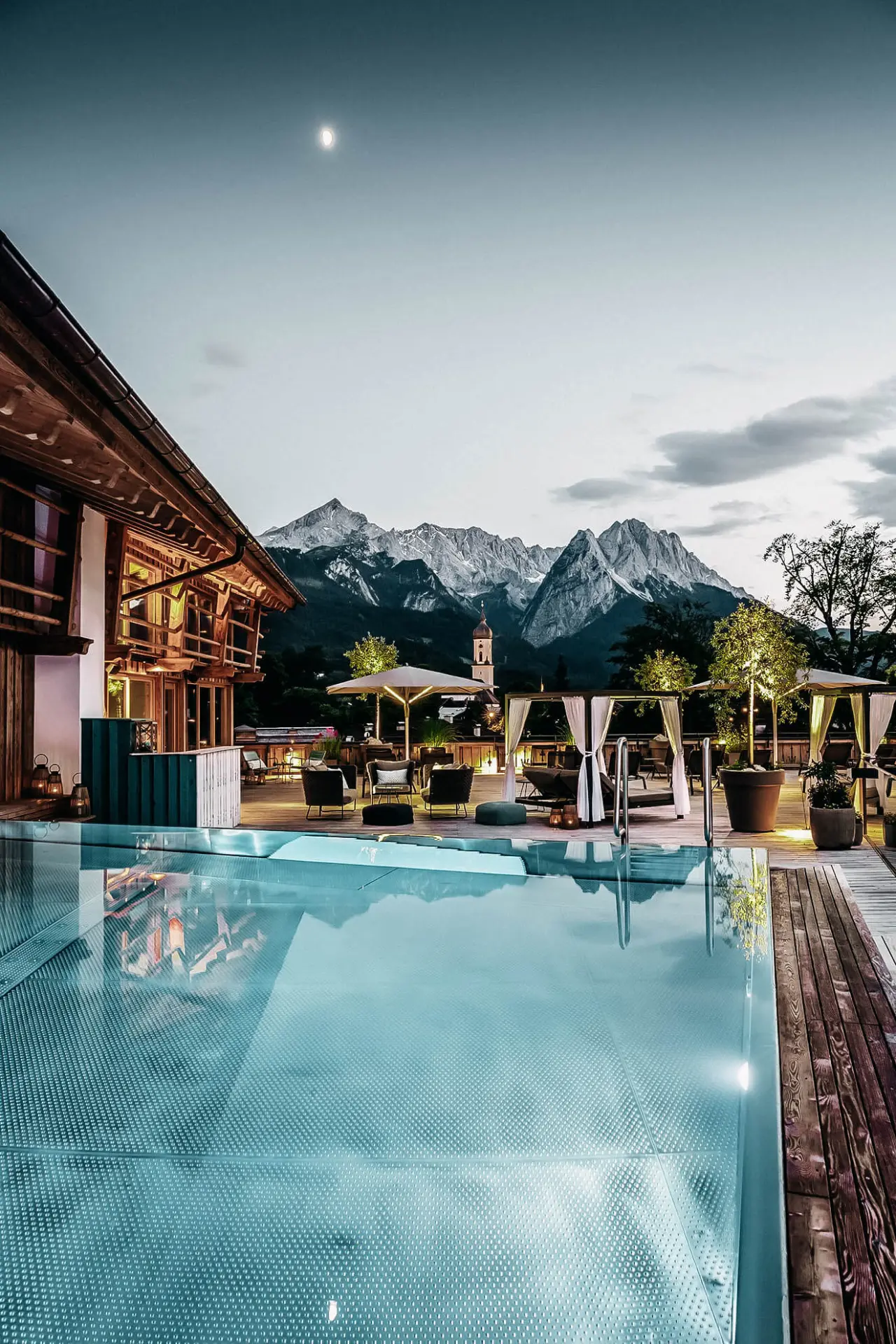 Beheizter Aussenpool mit Lounge-Bereich und Alpenpanorama bei Mondschein im Hotel WERDENFELSEREI