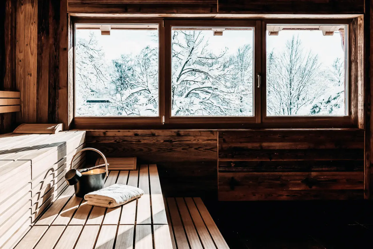 Gemütliche Holzsauna mit Blick auf verschneite Bäume im Winter im Hotel WERDENFELSEREI.