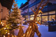 Festlich beleuchtete Aussenansicht des Hotel Zugspitze im Winter mit geschmücktem Weihnachtsbaum und Rentier-Dekoration.
