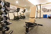 Fitnessraum im Hotel Zugspitze mit modernen Trainingsgeraeten und Bergpanorama-Wandbildern.