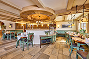 Gemütliches Restaurant im traditionellen Stil mit Holzbalken und grünen Sitzbänken im Hotel Zugspitze.