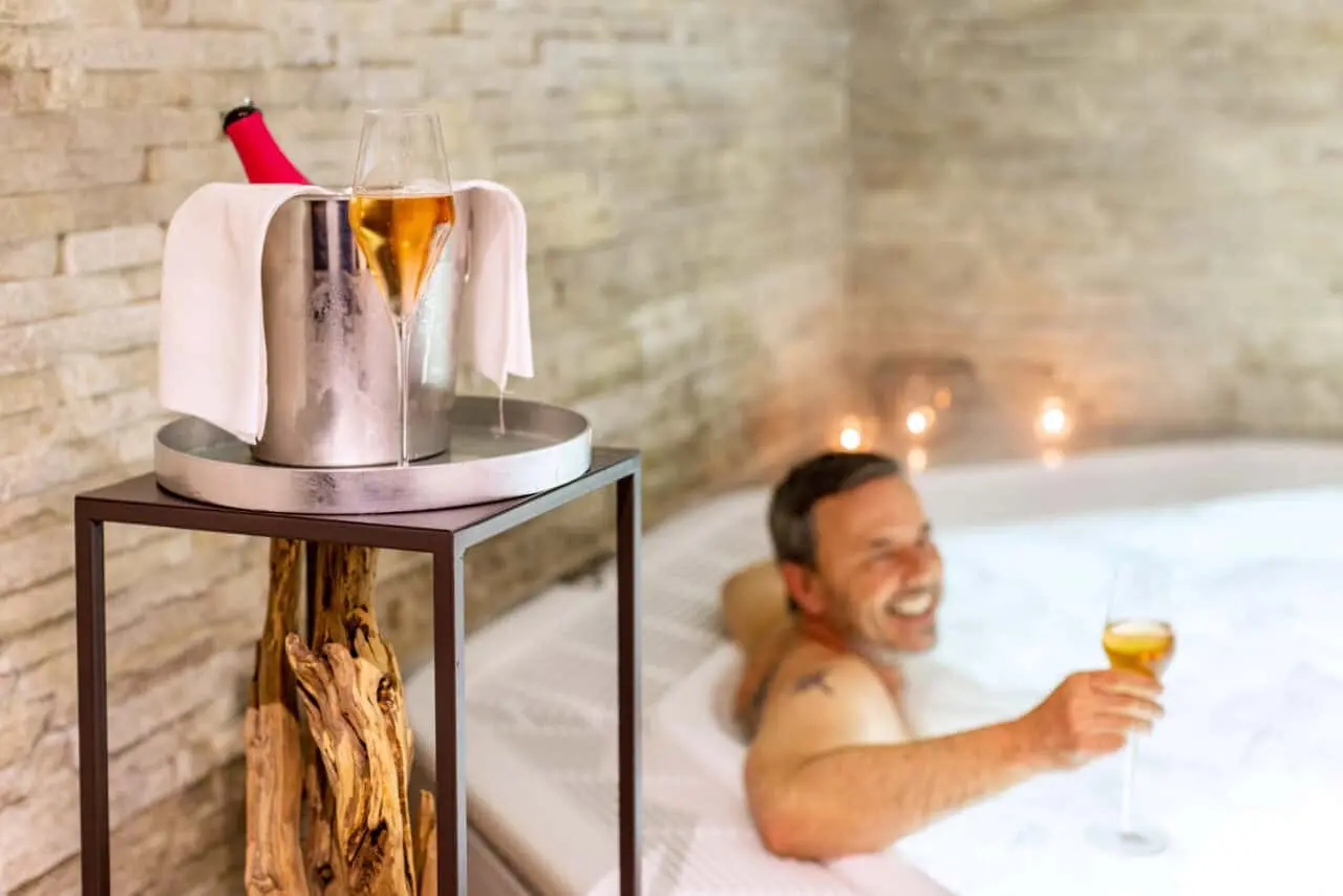 Mann genießt Champagner im Whirlpool des Best Western Plus Parkhotel Maximilian Spa.