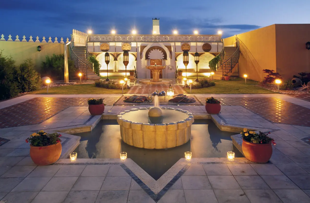 Beleuchteter orientalischer Innenhof mit Brunnen und exotischer Architektur im Wyndham Hotel Stralsund HanseDom bei Nacht.