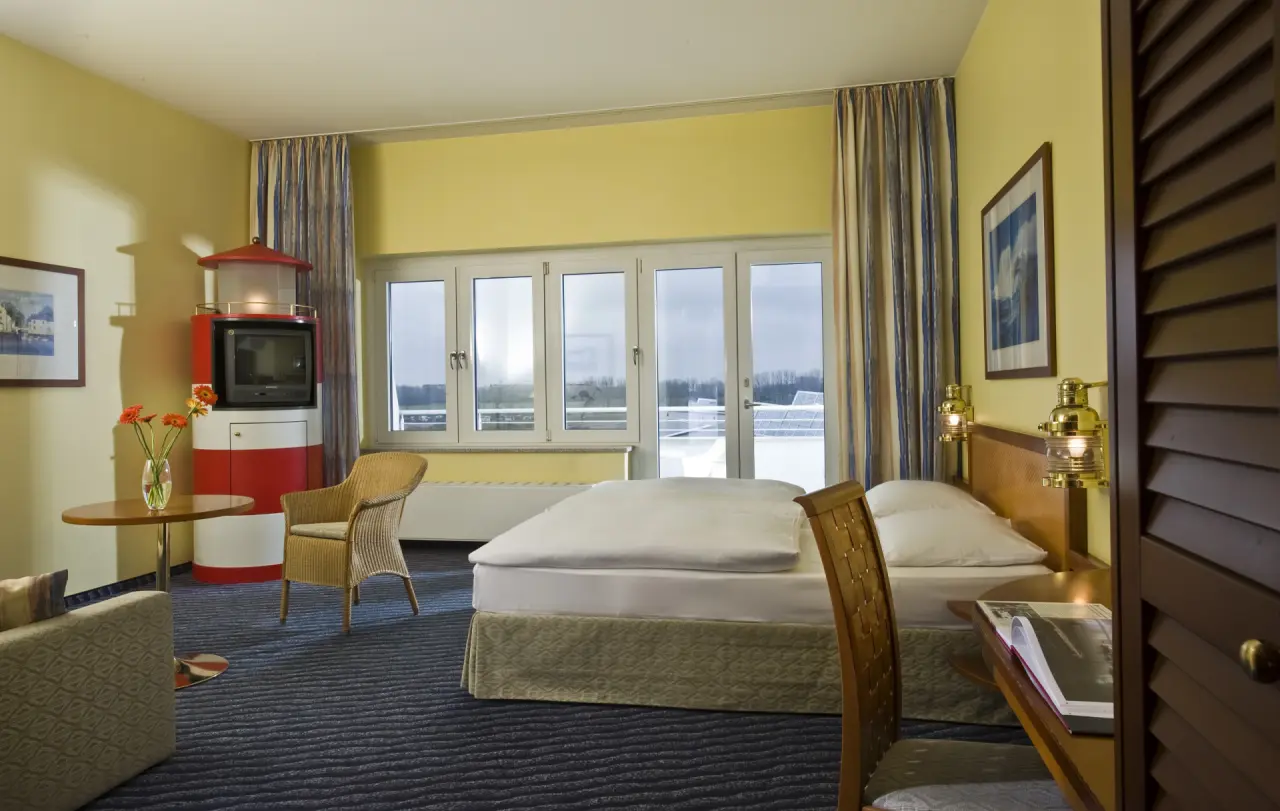 Gemütliches Hotelzimmer mit Doppelbett, Sitzbereich und Blick aus dem Fenster im Wyndham Hotel Stralsund HanseDom.