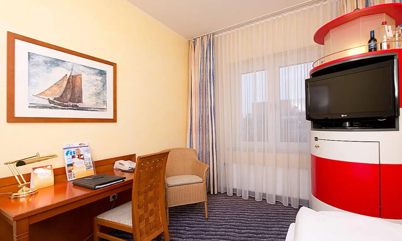 Gemütliches Hotelzimmer im Wyndham Hotel Stralsund HanseDom mit Schreibtisch, TV-Möbel im Leuchtturm-Design und Fenster.