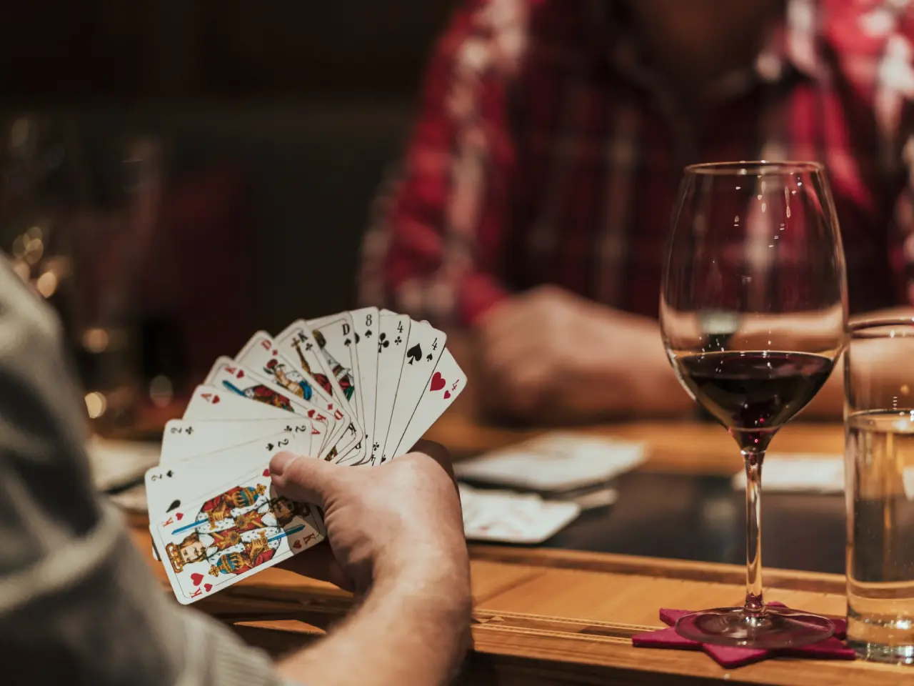 Gäste spielen Karten und genießen Wein in der gemütlichen Bar des Sporthotels Grandau.
