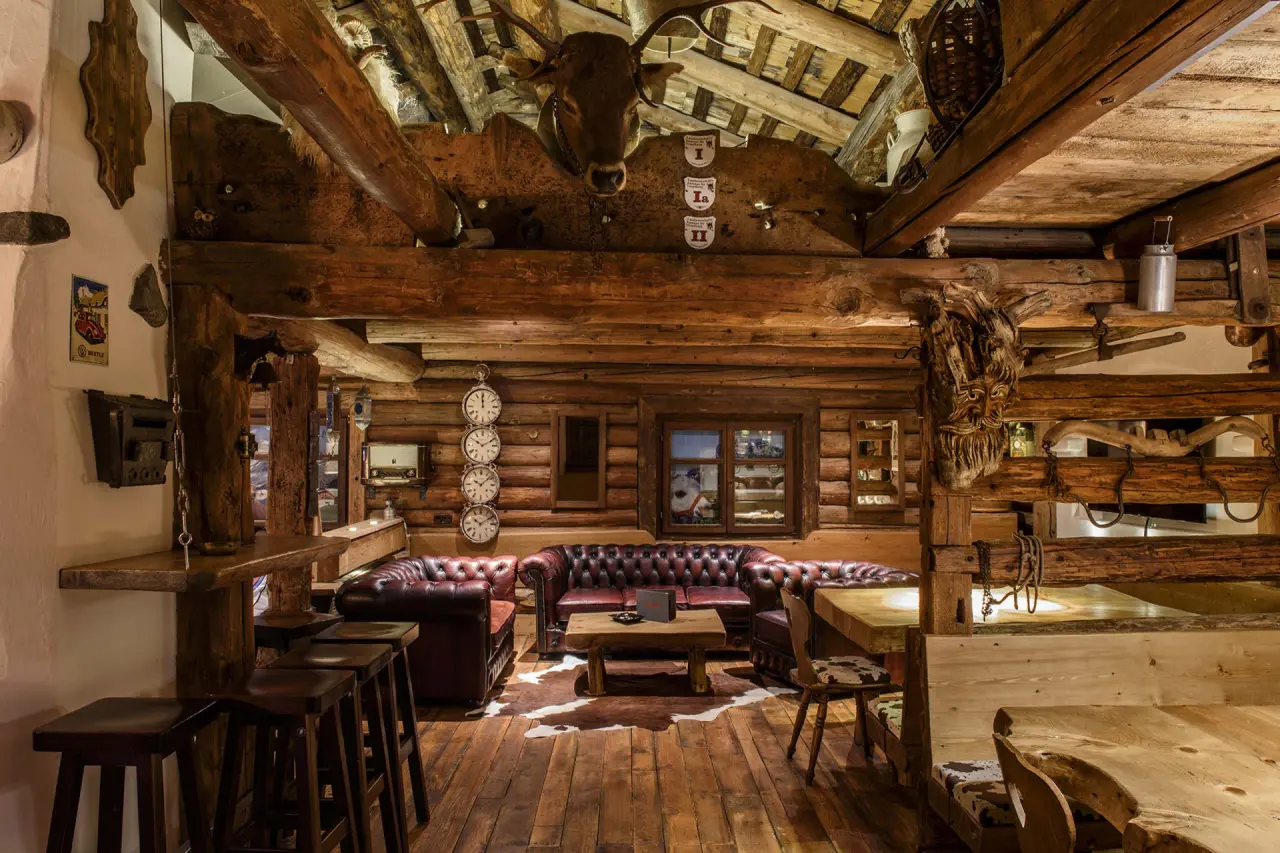 Rustikale Hotellounge im Sporthotel Grandau mit Holzbalken, Ledersofas und traditioneller Dekoration.