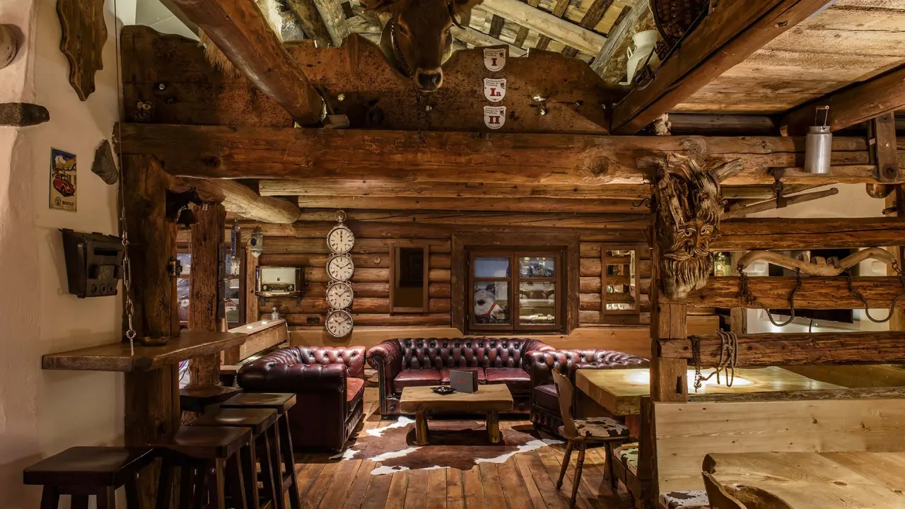 Gemütliche rustikale Lobby-Lounge mit Holzbalken, Ledersofas und Kuhfell im Sporthotel Grandau.