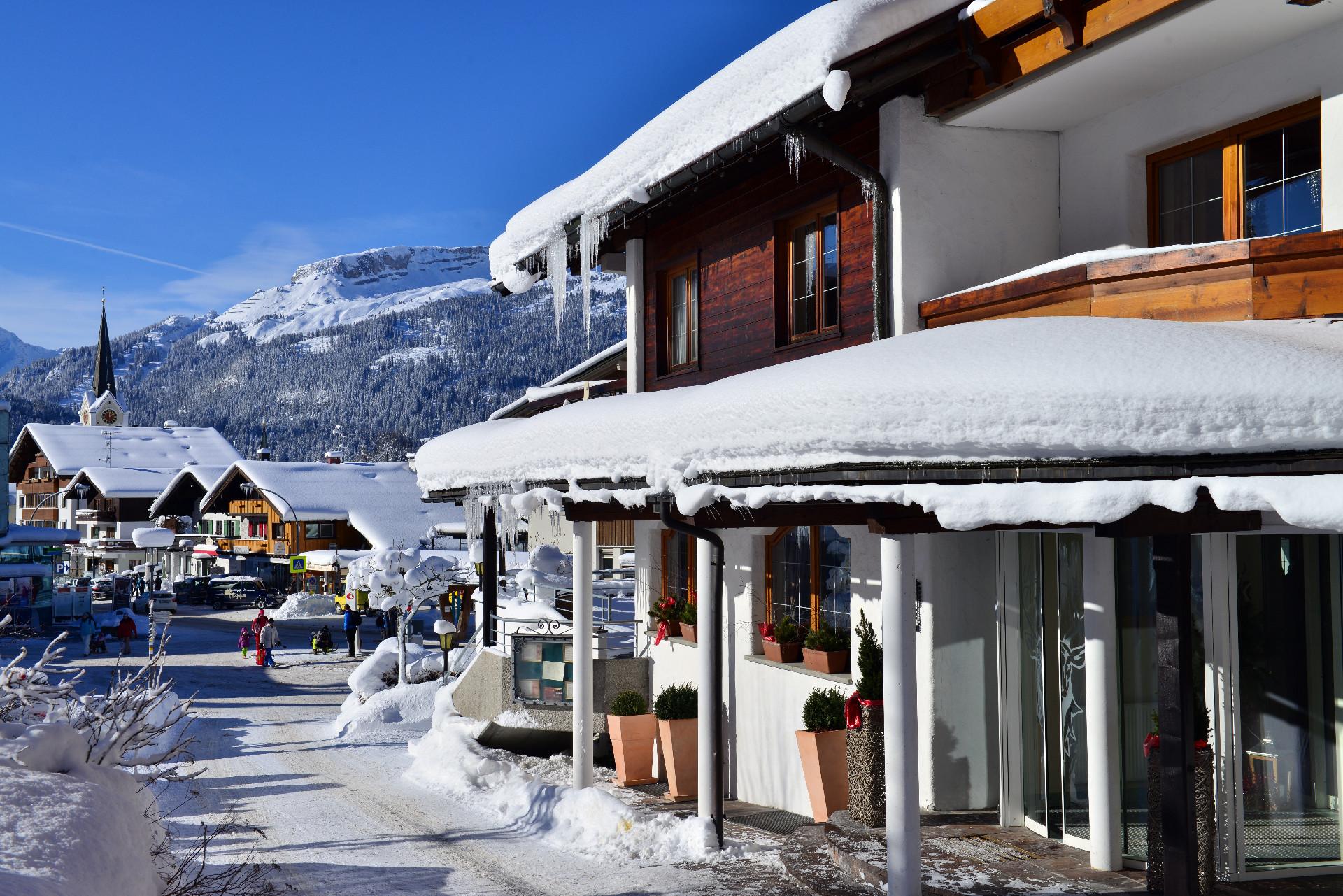 Hotel Jagdhof in Riezlern – Winterliche Ansicht des Hotels an der Straße mit Schnee | Wellnesshotel Kleinwalsertal