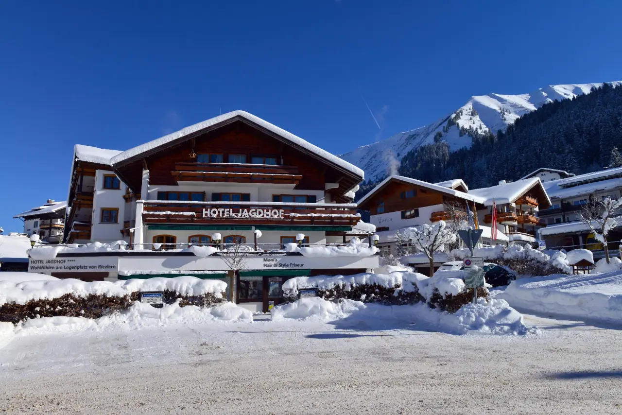 Hotel Jagdhof in Riezlern – Majestätische Winteransicht des Hotels mit verschneiten Bergen | Wellnesshotel Kleinwalsertal