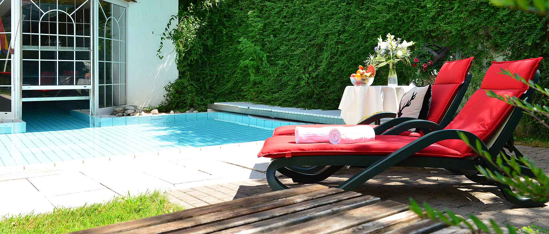 Hotel Jagdhof in Riezlern – Entspannende Liegestühle am kleinen Außenpool im Grünen | Wellnesshotel Kleinwalsertal