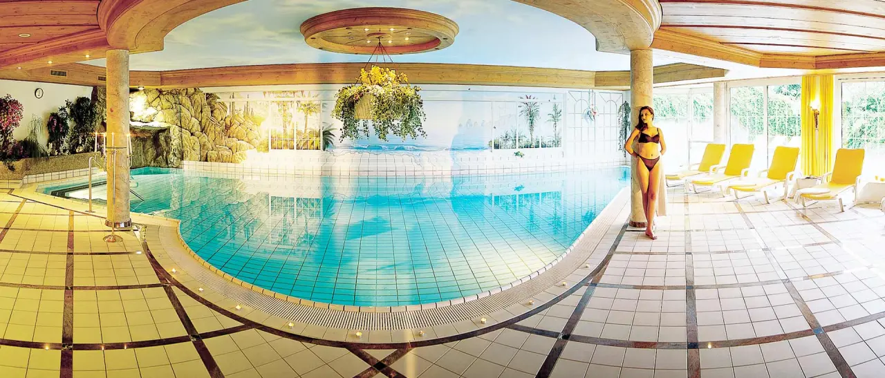Grosszügiger Innenpool mit Liegebereich und Wandmalereien im Wellnessbereich des Hotel Jagdhof.