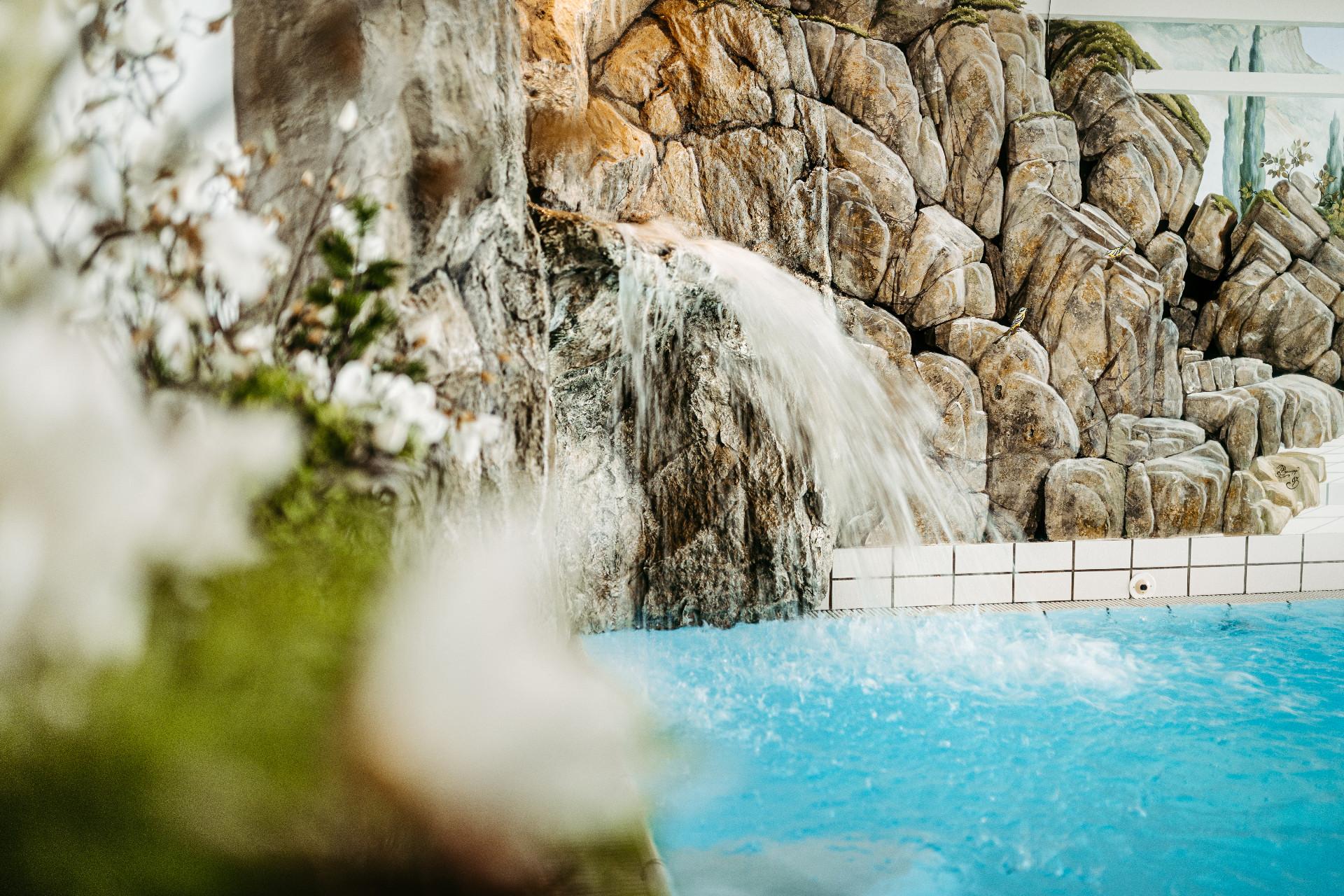 Hotel Jagdhof in Riezlern – Detailaufnahme eines Wasserfalls im Innenpoolbereich | Wellnesshotel Kleinwalsertal