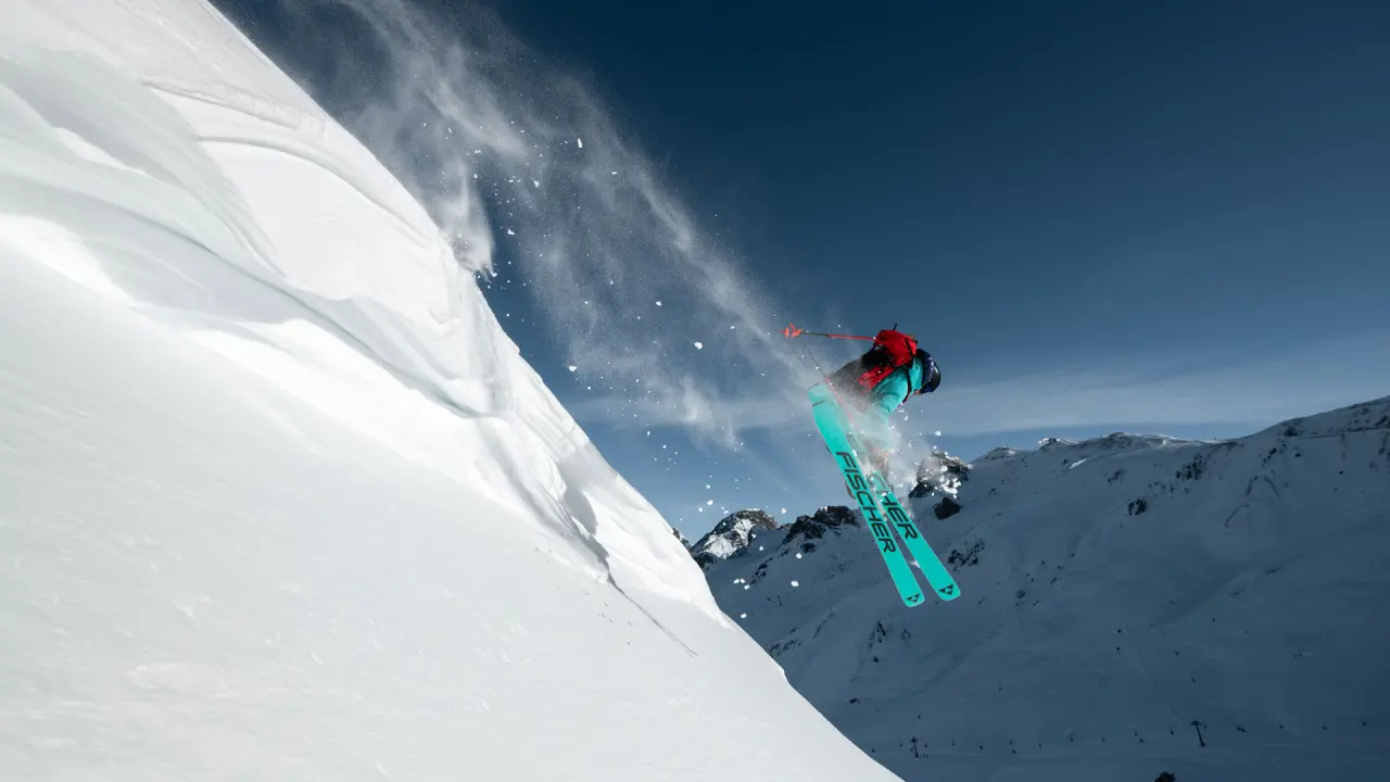 Freeride-Skifahrer springt über eine Schneewechte in den Alpen, mit Blick auf die Bergwelt rund um das Hotel Salnerhof.