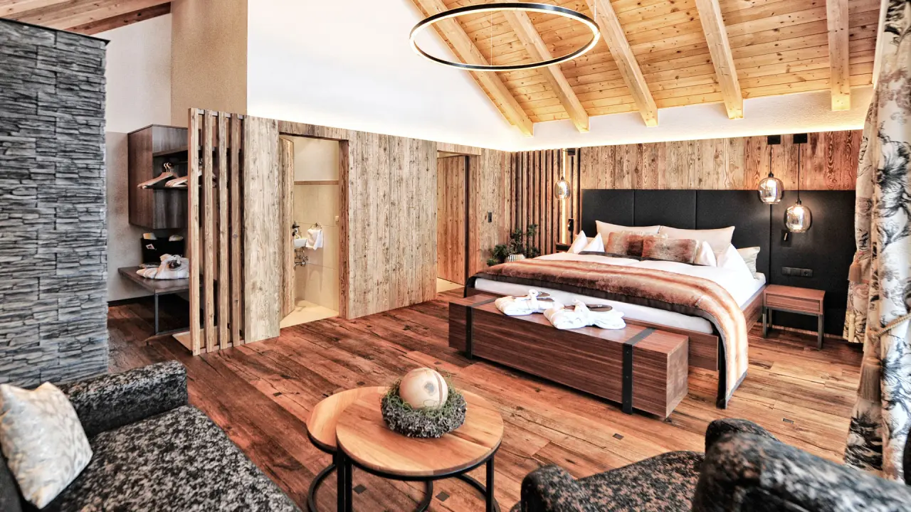Komfortables Doppelzimmer im alpinen Stil mit Holzbalkendecke, Kingsize-Bett und Sitzecke im Hotel Salnerhof.