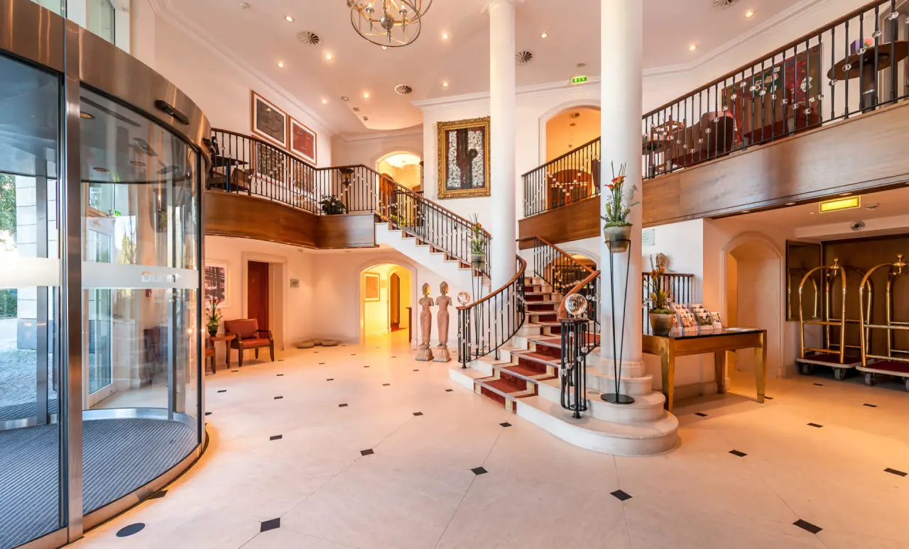Elegante Hotellobby mit geschwungener Treppe und luxuriösem Ambiente im Maison Messmer.