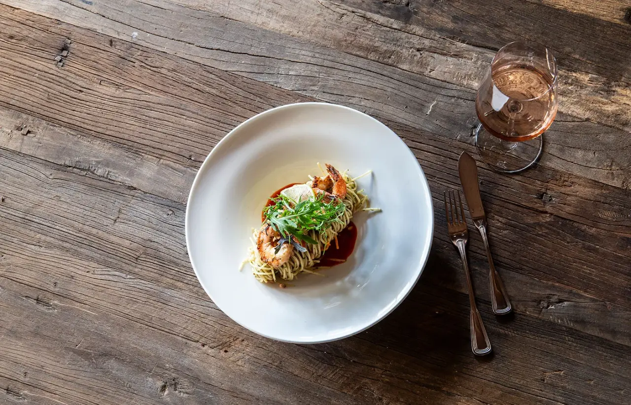 Exquisites Garnelen-Pasta-Gericht mit Roséwein auf rustikalem Holztisch im Restaurant des Hotel das Alois ****s.