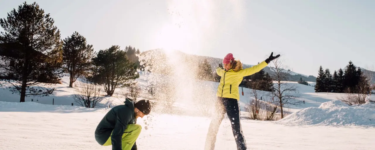 Gäste des LEBE FREI Hotel DER LÖWE genießen fröhliches Schneevergnügen in der winterlichen Berglandschaft.
