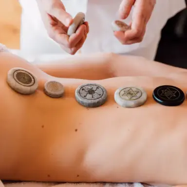 Spa-Behandlung mit Chakra-Steinen auf dem Rücken im LEBE FREI Hotel DER LÖWE.