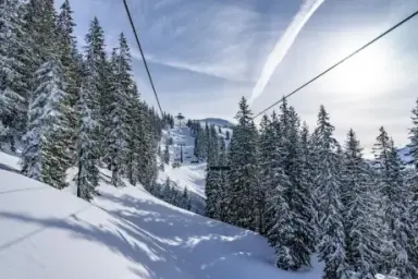 Verschneite Berglandschaft mit Skilift und Tannenbäumen im Winter nahe Hotel Erika.