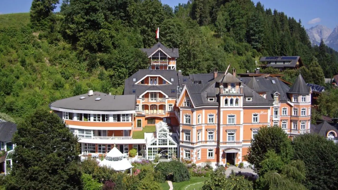 Gesamtansicht des Hotel Erika, eingebettet in grüne Wälder mit Bergpanorama im Hintergrund.