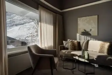 Stilvoller Wohnbereich einer Suite im Hotel Erika mit bequemen Möbeln und winterlichem Ausblick.