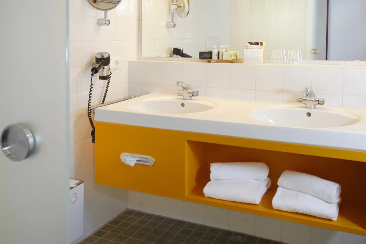 Modernes Badezimmer mit Doppelwaschbecken und gelbem Unterschrank im Hotel an der Therme Bad Orb.