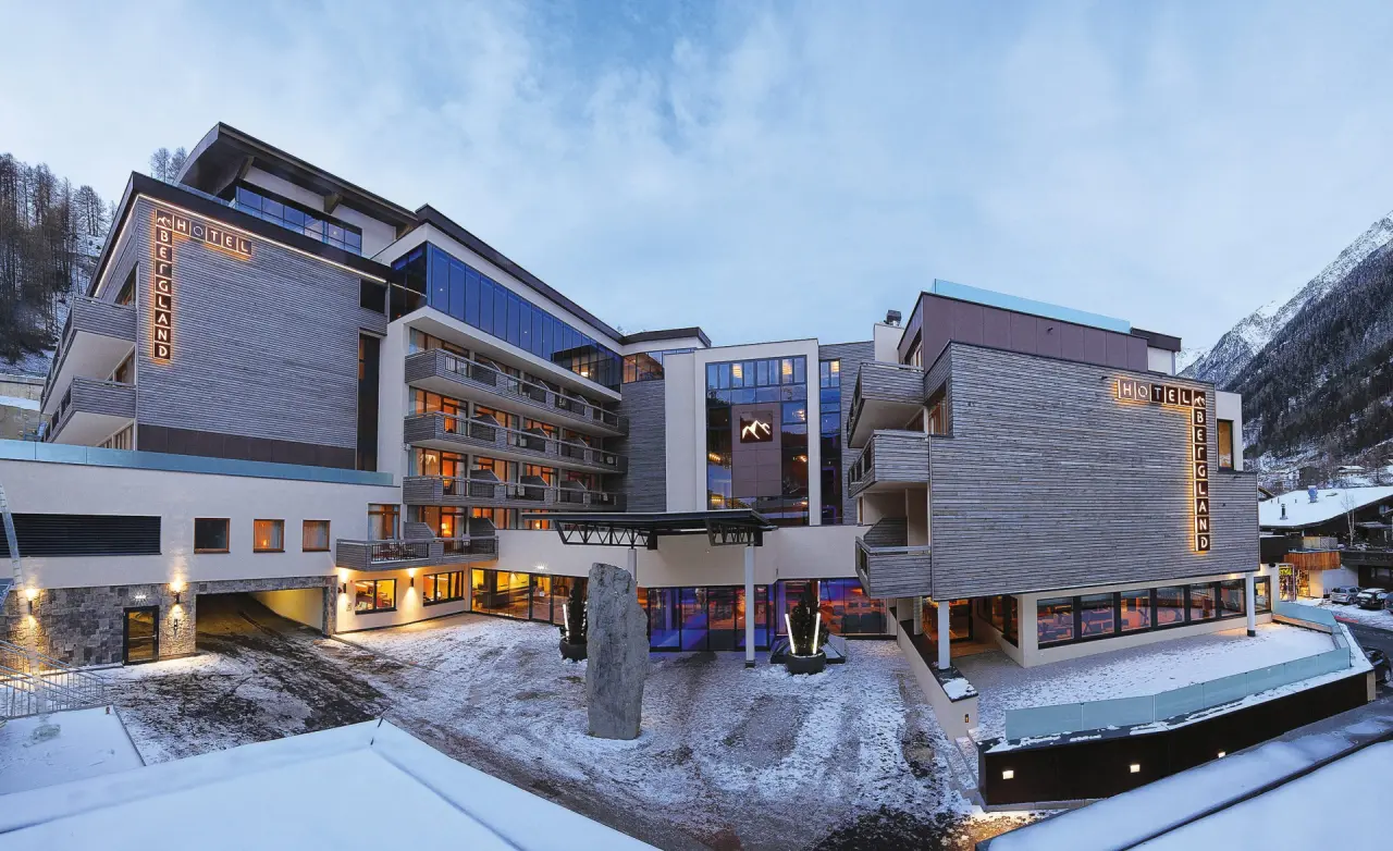 Modernes Bergland Hotel Sölden im Winter mit Schnee und beleuchteter Fassade vor alpiner Kulisse.