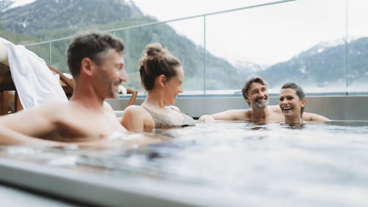 Glückliche Gäste entspannen im Infinity-Aussenpool des Bergland Hotel Sölden mit Alpenpanorama.