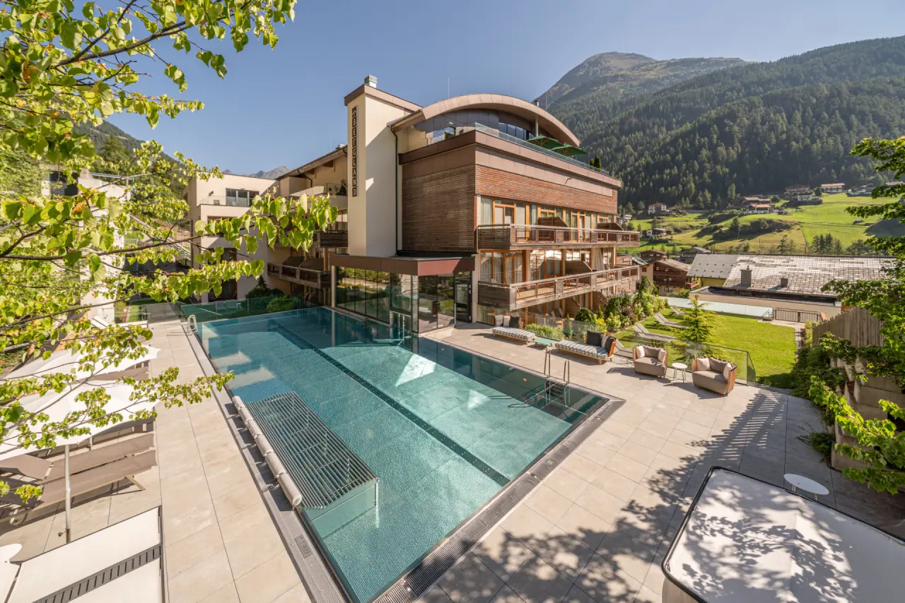 Aussenpool mit Sonnenterrasse und Alpenpanorama im Bergland Hotel Sölden. Modernes Wellnesshotel in den Tiroler Alpen.