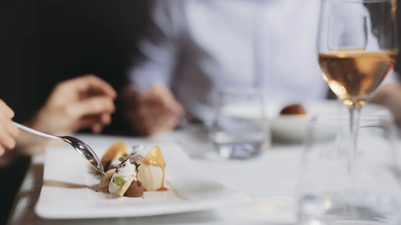 Feines Dessert mit Karamell und Sahne im Restaurant des Bergland Hotel Sölden, serviert mit einem Glas Wein.