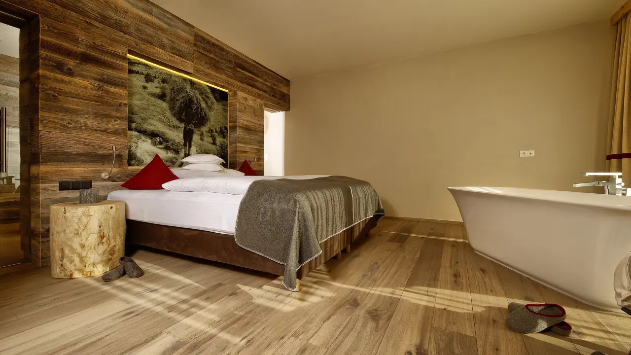 Modernes Doppelzimmer mit freistehender Badewanne und Altholz-Design im Bergland Hotel Sölden.