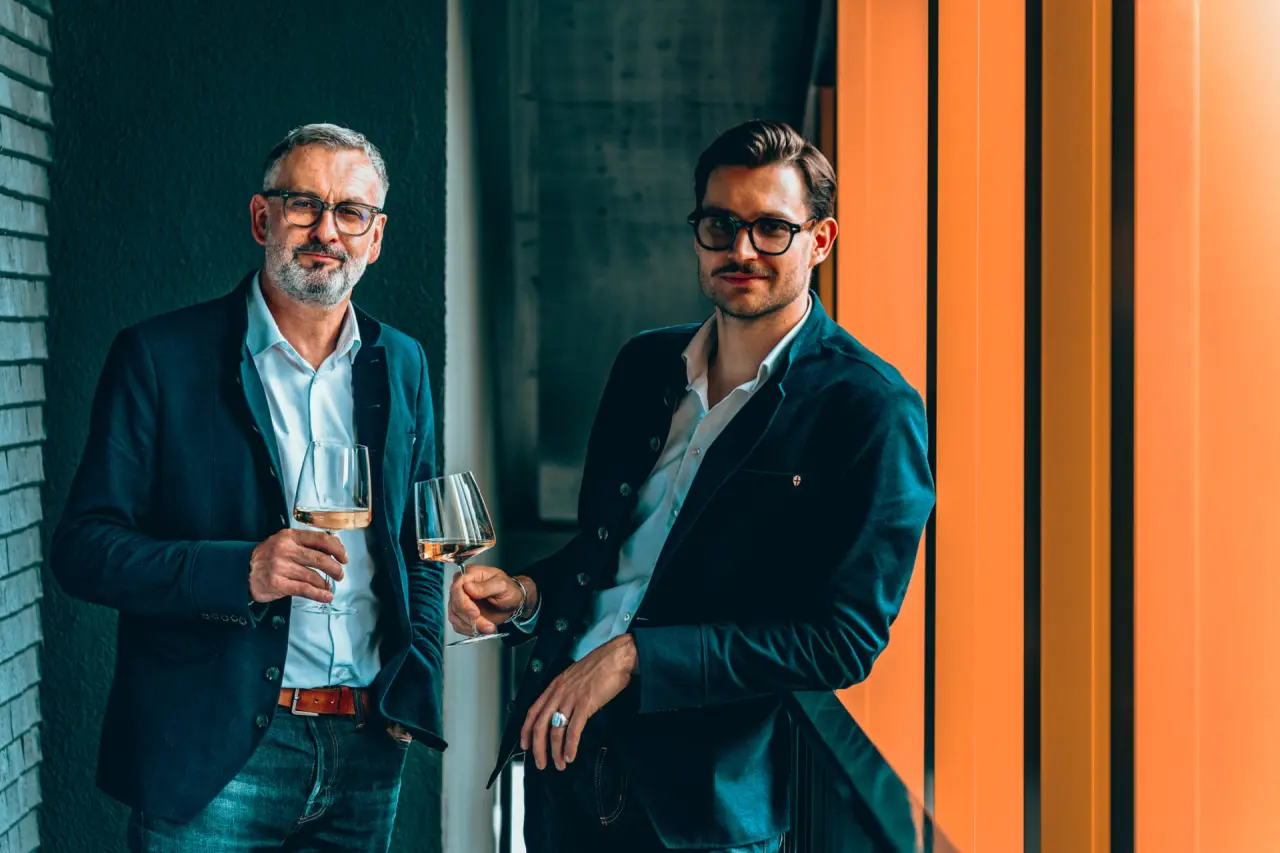 Zwei Männer mit Weingläsern in stilvoller Umgebung des Hotel Alpenkönig.
