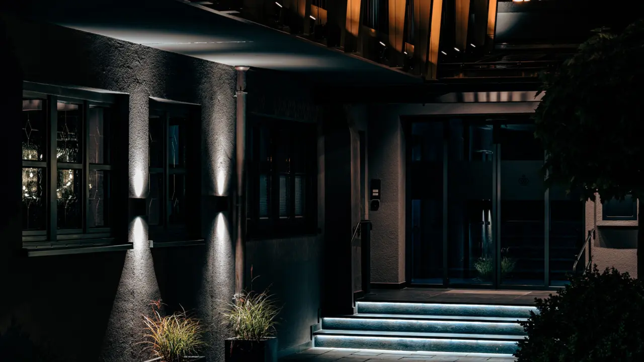 Beleuchteter Eingangsbereich des Hotel Alpenkönig bei Nacht mit modernen Stufenlichtern und Wandbeleuchtung.