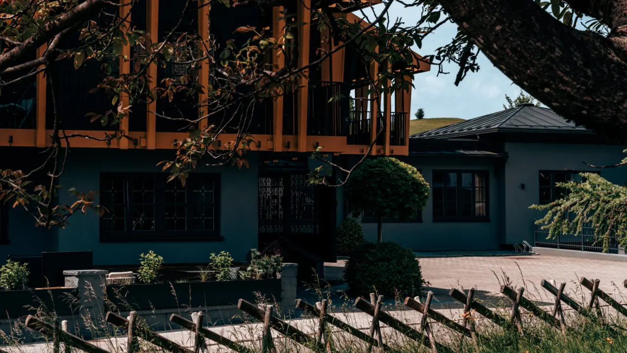 Aussenansicht des Hotel Alpenkönig mit moderner Architektur und Holzelementen, umgeben von Bäumen und einem Holzzaun.