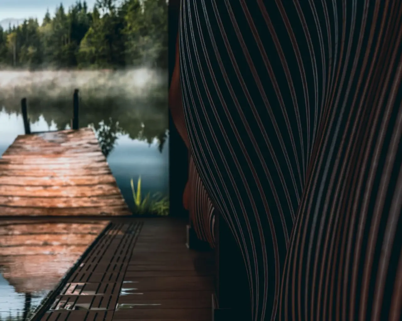 Malerischer Nebelsee mit Holzsteg und Waldkulisse am Hotel Alpenkönig, ideal zur Entspannung.