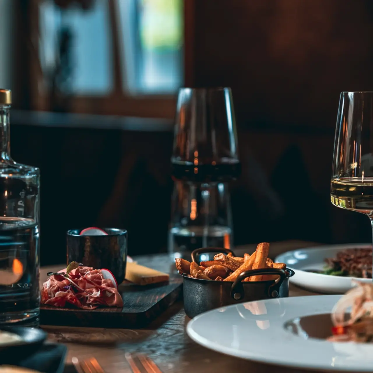 Ansprechend gedeckter Tisch mit regionalen Spezialitäten, Wein und Wasser im Restaurant des Hotel Alpenkönig.