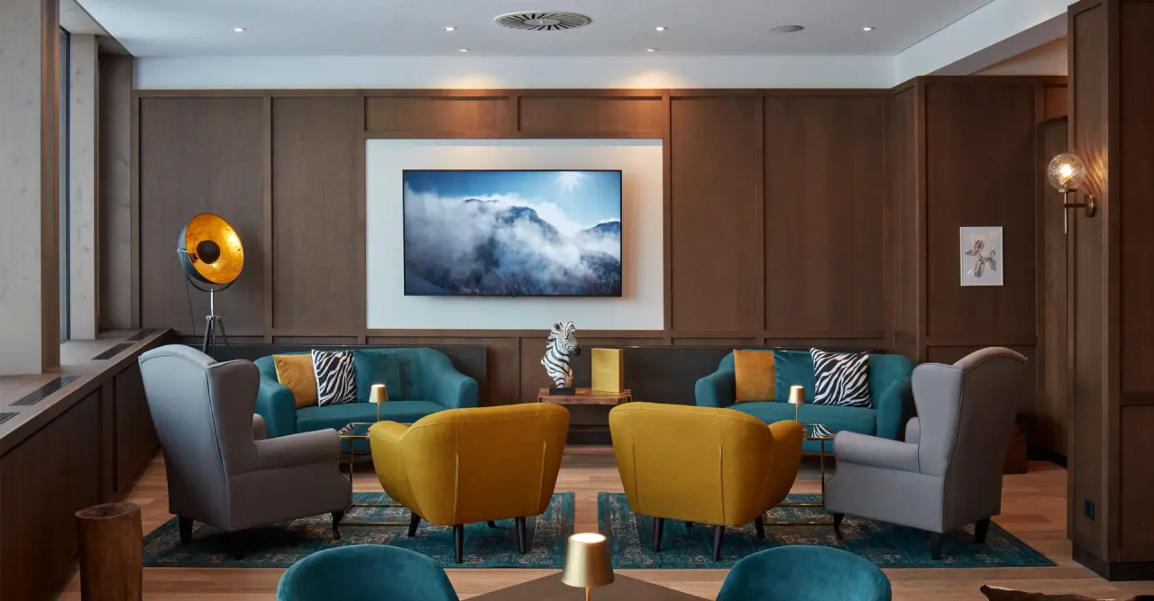 Moderne Hotellounge mit bequemen Sesseln und Sofas in warmen Farben im Hotel & Spa Wulfenia. Einladender Aufenthaltsbereich.